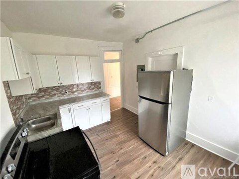 A kitchen with a black fridge and a stove top oven.