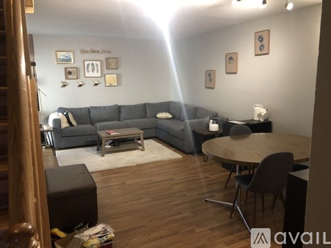A living room with a grey sofa, a wooden coffee table, and a round wooden table with chairs.