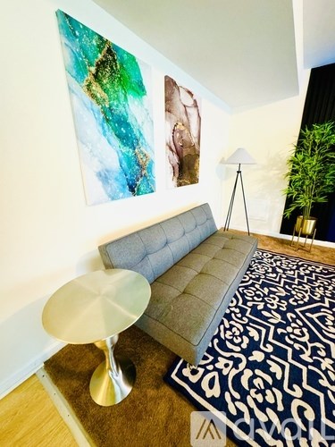 A grey sofa with a white table in front of it.