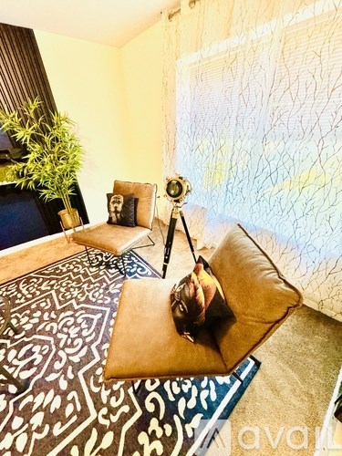 A woman is sitting on a cushion in a room with a patterned carpet.
