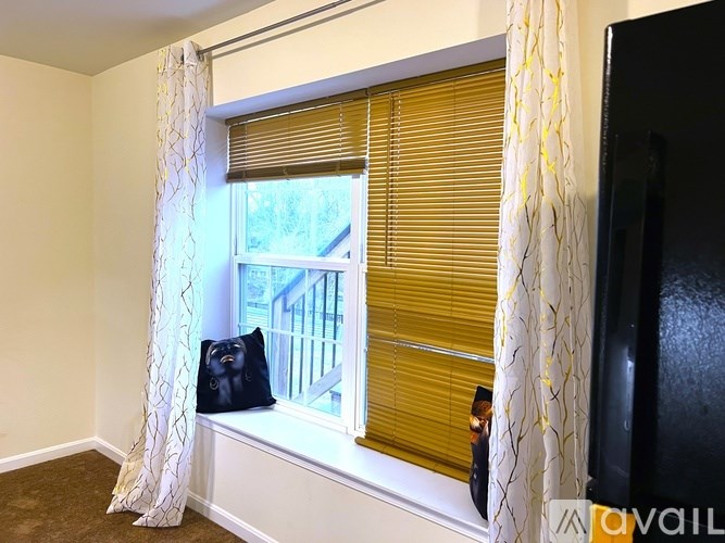 A room with a window, curtains, and a bag on the window sill.