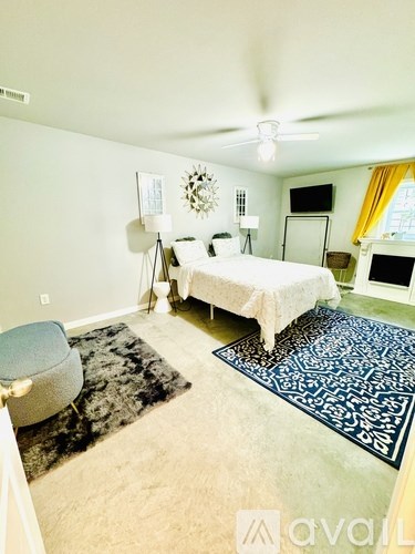 A bedroom with a bed, chair, and rug.