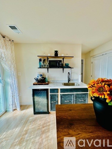 A kitchen with a black fridge and a wooden table with a vase of flowers on it.
