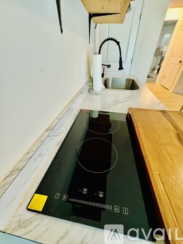 A black induction cooktop is installed on a marble countertop.