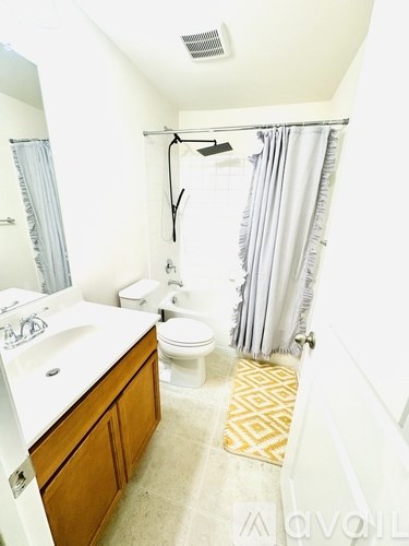 A bathroom with a white sink, toilet and a shower curtain.