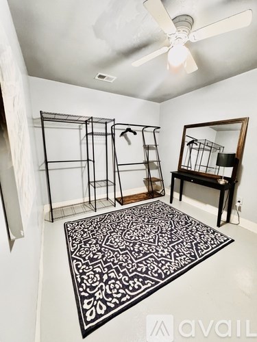 A room with a rug, a mirror, and a shelf.