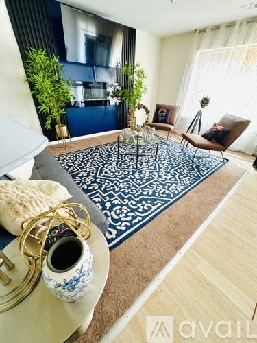 A living room with a blue and white rug, a coffee table with a vase and a bowl on it, and a couch.