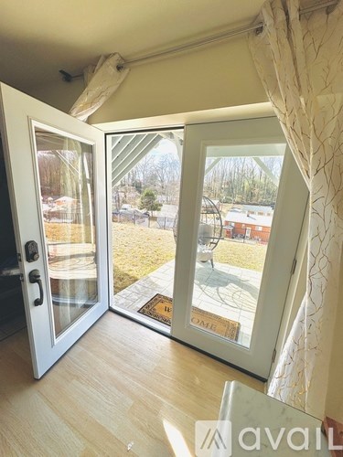 A white door with a glass window is open to a backyard.