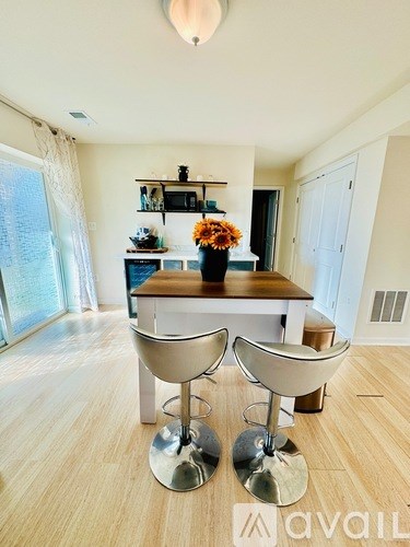 A modern dining room with a wooden table and two chairs with chrome legs.