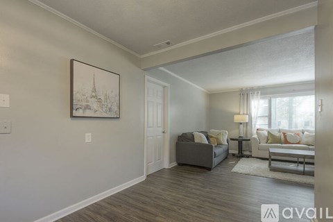 A living room with a grey couch and a painting on the wall.