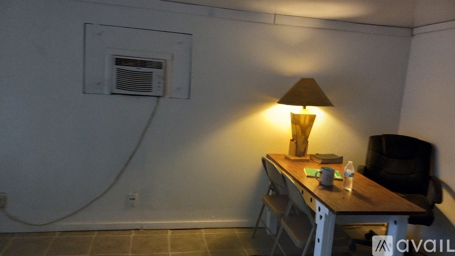 A lamp on a desk in a room with a white wall and a window vent.