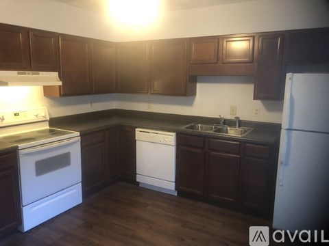A kitchen with white appliances and brown cabinets.