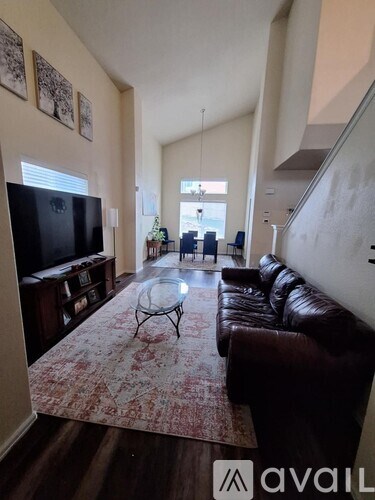 A living room with a brown leather couch and a television.