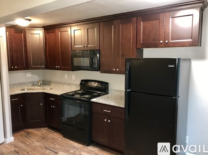 A kitchen with black appliances and brown cabinets.