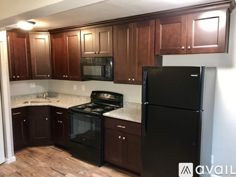A kitchen with black appliances and brown cabinets.