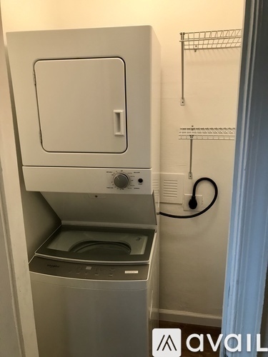 A small white cabinet with a door and a shelf is mounted on a wall.