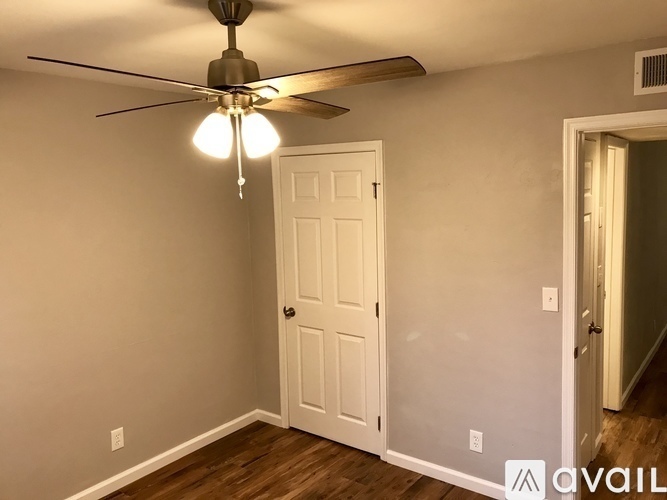 A room with a ceiling fan and a white door.
