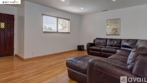 A living room with a brown leather couch and a wooden floor.