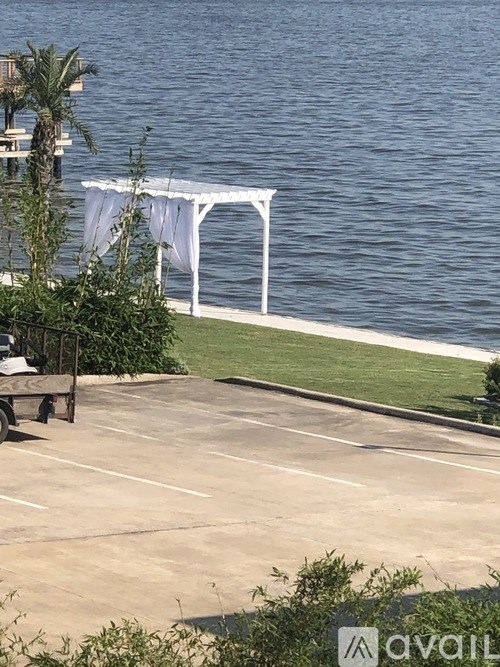 A parking lot with a white canopy and a body of water in the background.
