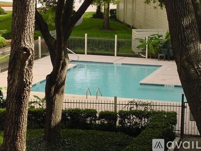 A pool surrounded by a fence and trees.