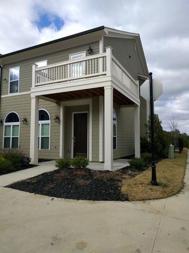 A small house with a balcony and a brown door.