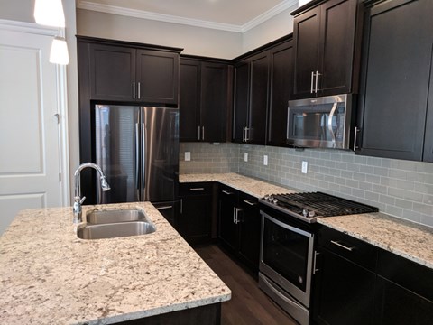 A kitchen with black cabinets and a granite countertop.