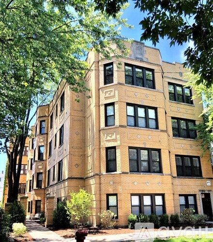 A tall building with many windows and a tree in front of it.