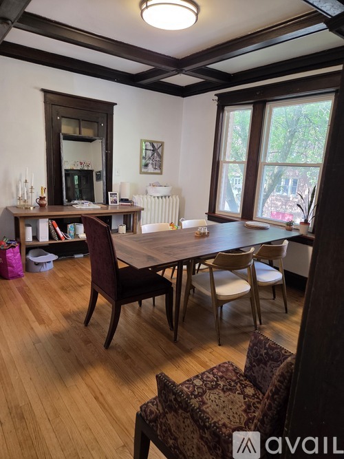 A room with a table, chairs and a bookcase.