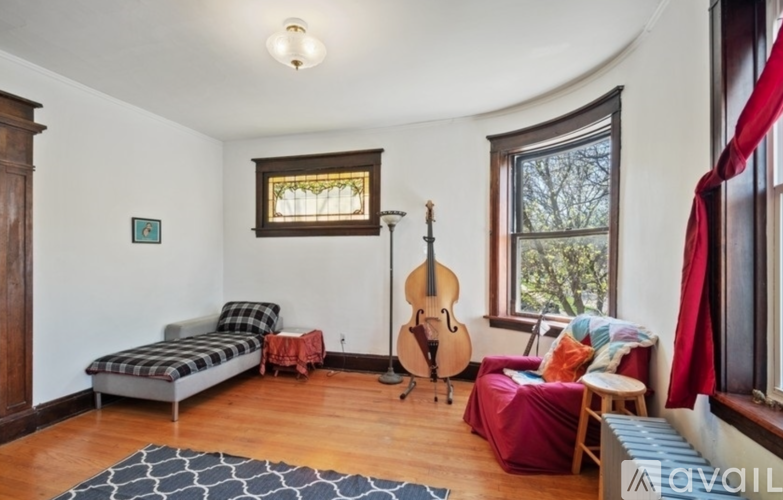 A living room with a couch, a guitar, and a window.