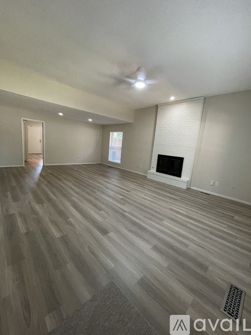 A spacious room with a fireplace and wood flooring.