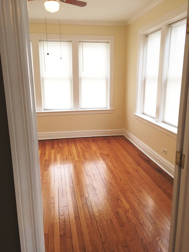 A room with wooden floors and two windows.
