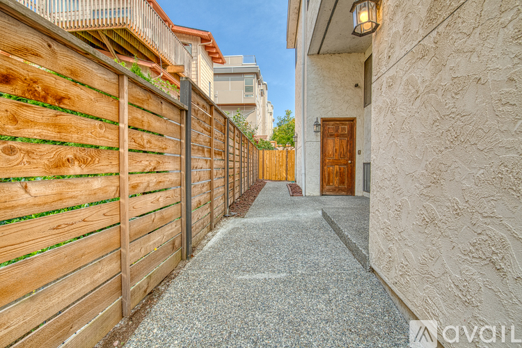 A narrow alley with a wooden fence on the left and a building with a wooden door on the right.