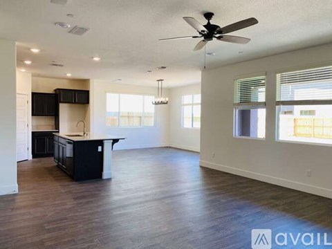 A spacious living room with a kitchen area in the background.
