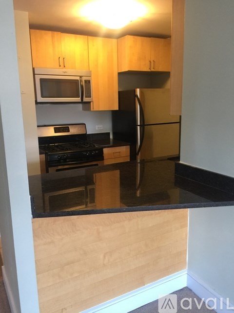 A kitchen with wooden cabinets and black countertops.