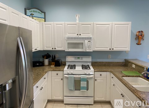 A kitchen with white cabinets and a stainless steel refrigerator.