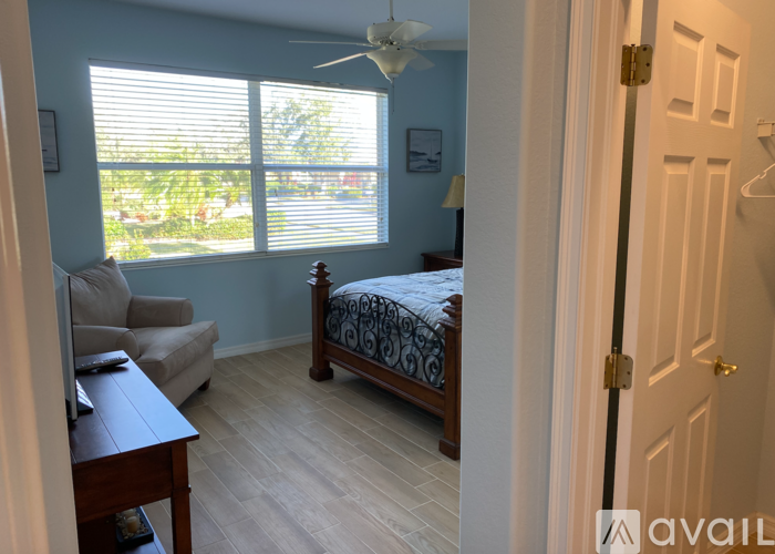 A bedroom with a bed, a couch, and a ceiling fan.