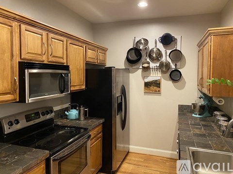 A kitchen with wooden cabinets and a black refrigerator.
