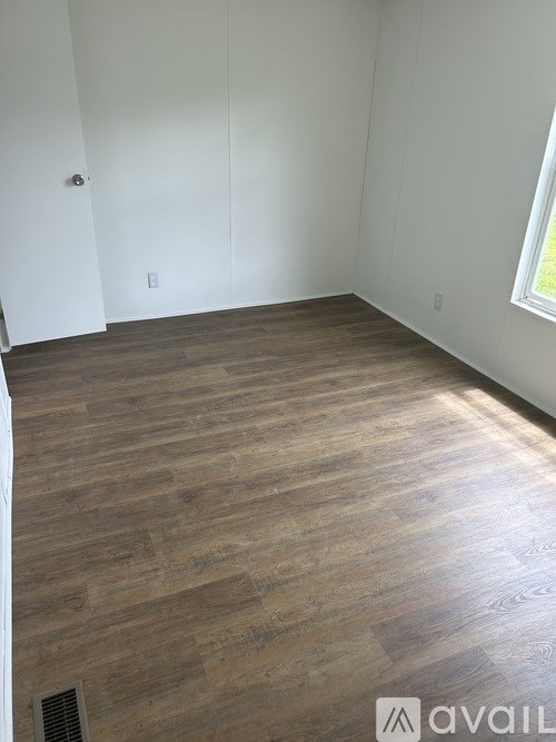A room with wooden flooring and white walls.