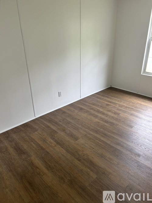 A room with wooden flooring and white walls.
