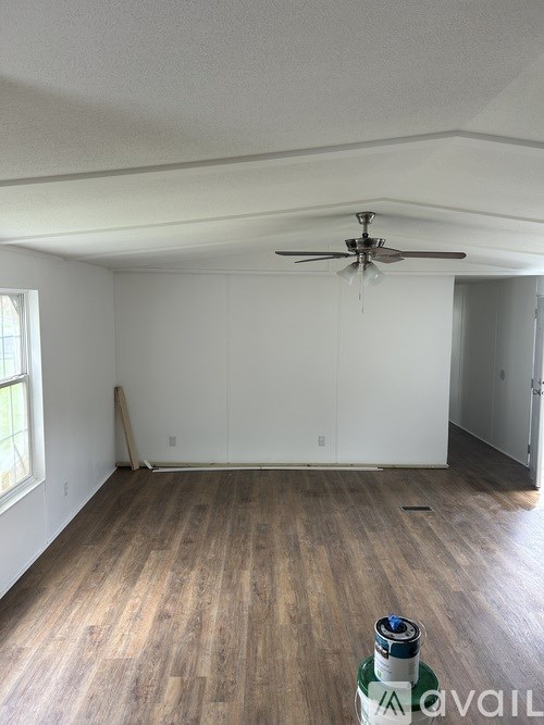 A room with a ceiling fan and wooden flooring.