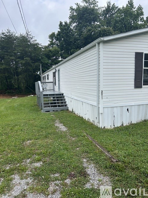A white mobile home with a grey ramp outside.