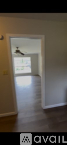 A room with a ceiling fan and a doorway leading to another room.