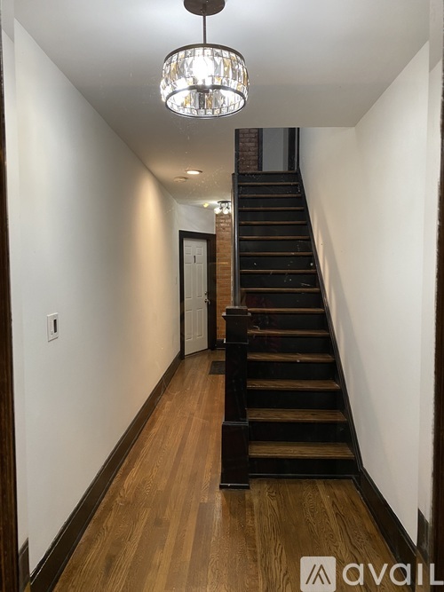 A long hallway with a staircase and a chandelier.