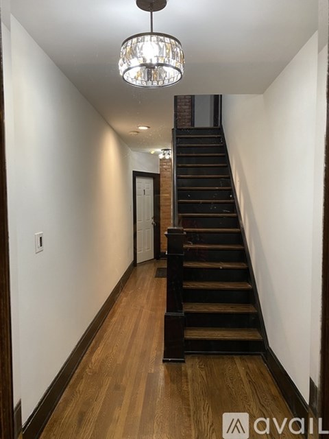 A long hallway with a staircase and a chandelier.
