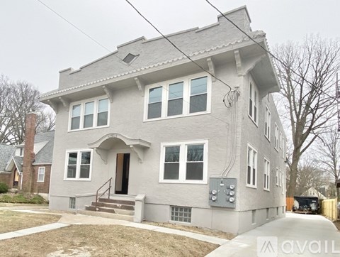 A grey house with a brown door and windows.