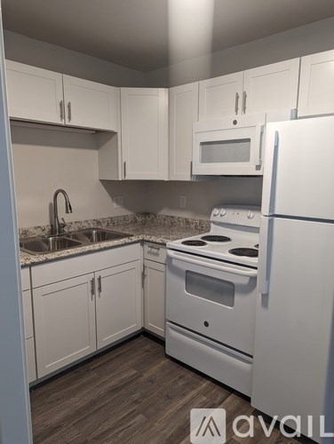 A kitchen with white appliances and cabinets.