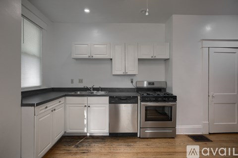 A kitchen with white cabinets and a wooden floor.