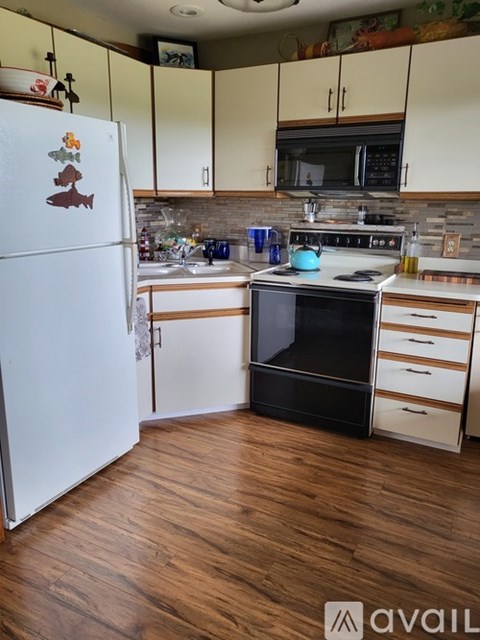 A kitchen with a white fridge and black stove top oven.
