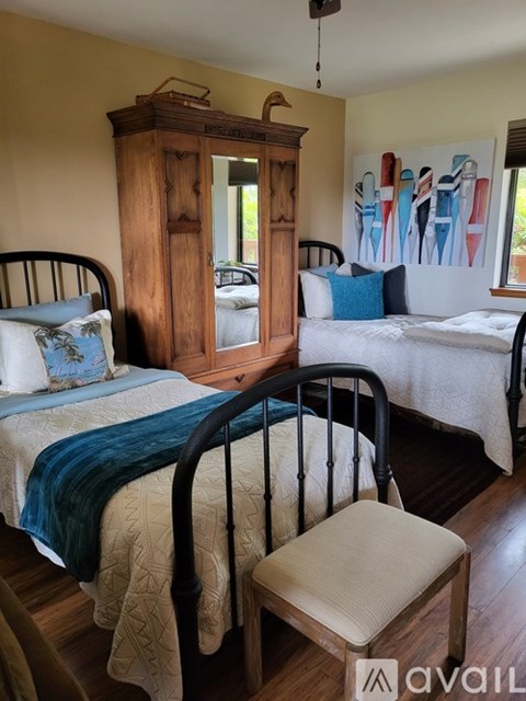 A bedroom with a bed, chair, and wooden cabinet.