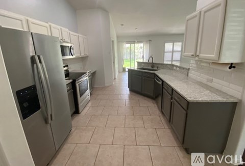 A kitchen with a refrigerator, microwave, oven, and sink.